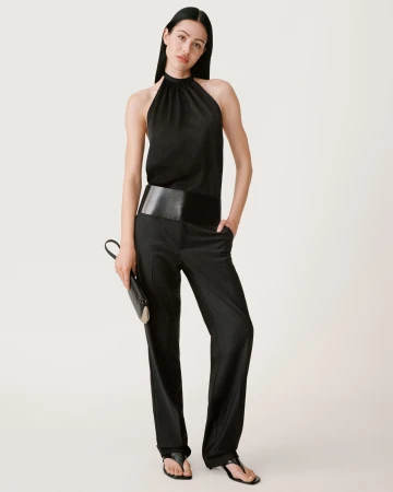 Model in a black halter top and black trousers against a neutral white background