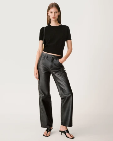 Model in black top and leather trousers posing against a bright white background for Zara campaign