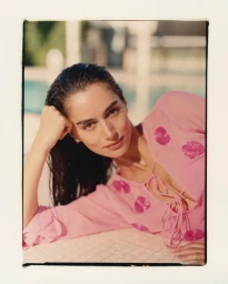 Model Maia Cotton in a pink patterned top posing by a pool for Anthropologie Miami project