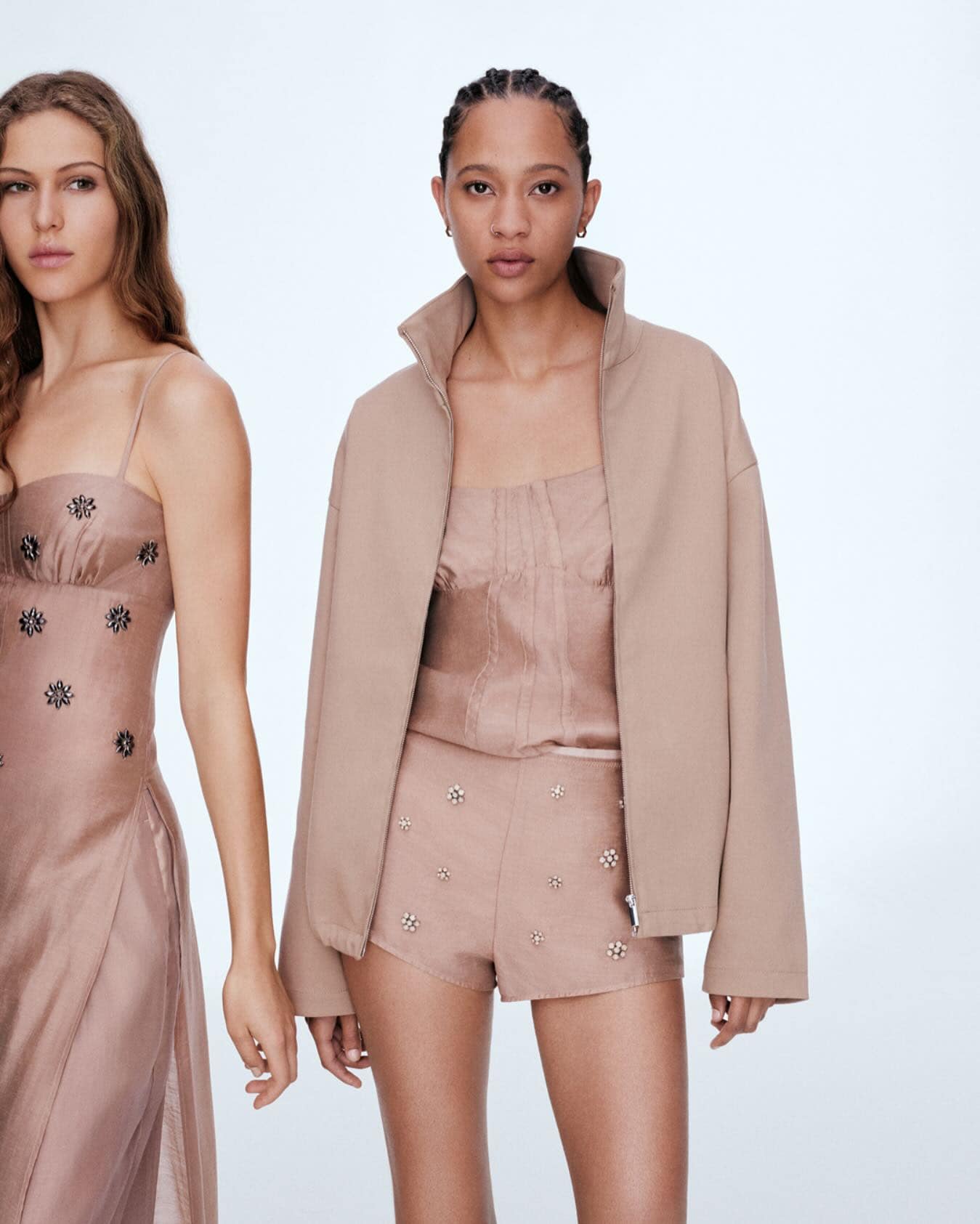 Two female models wearing beige attire against a bright white background for H&M Spring 2025 campaign.