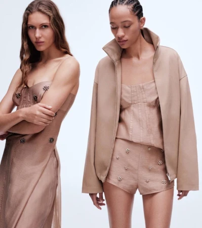 Two female models wearing beige embellished outfits against a white backdrop for H&M Notes on Being spring 2025 campaign.