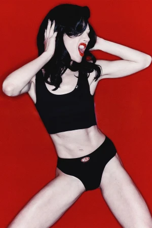 Model in black underwear posing against a vibrant red background for Willy Chavarria