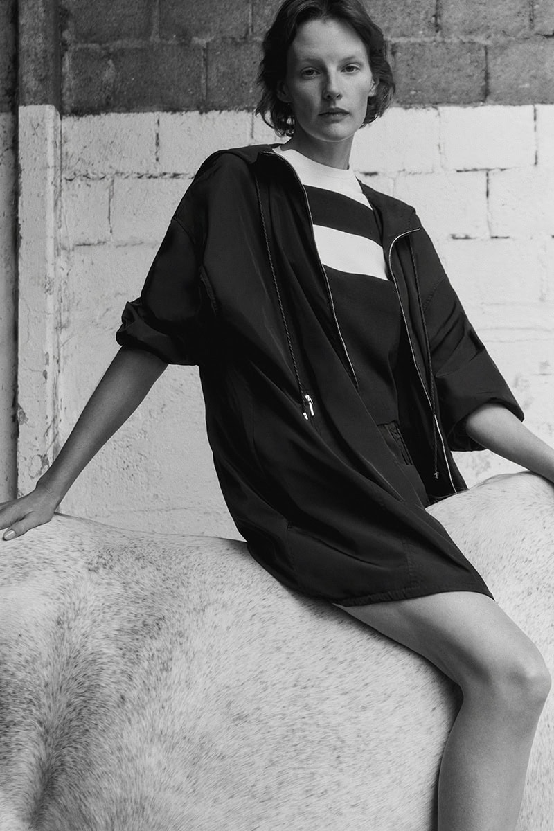 Model Sara Blomqvist in a dark hooded jacket and striped top seated on a white horse for the Giada Leisure campaign