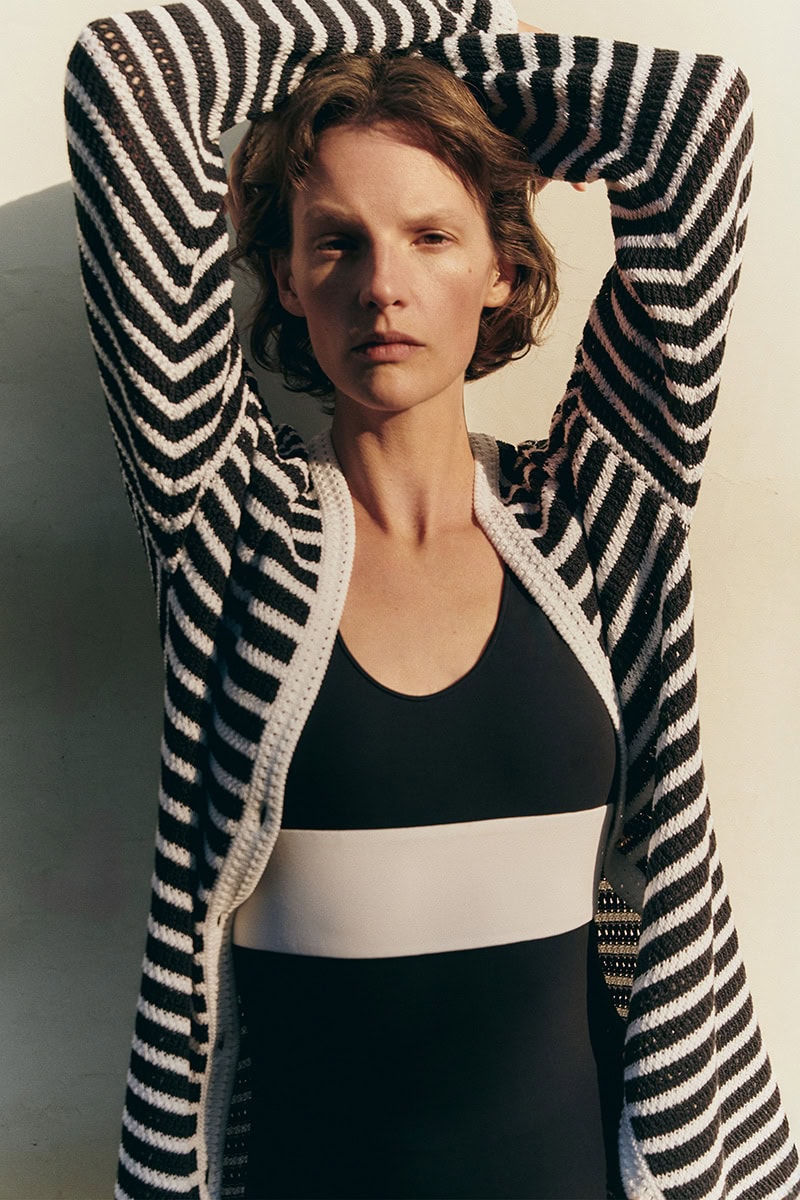Model Sara Blomqvist in a striped cardigan and black top posing against a plain wall for Giada