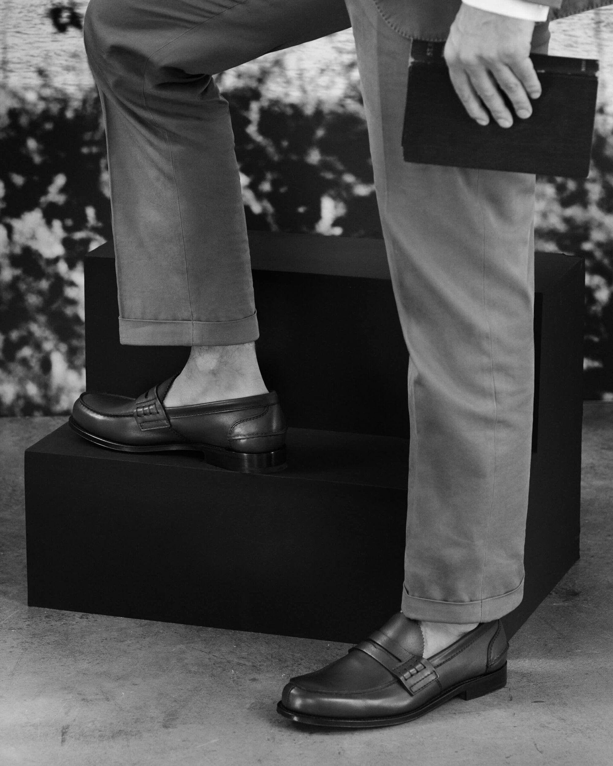 Close-up of a man wearing leather loafers standing on black steps for Church's Spring 2025 campaign