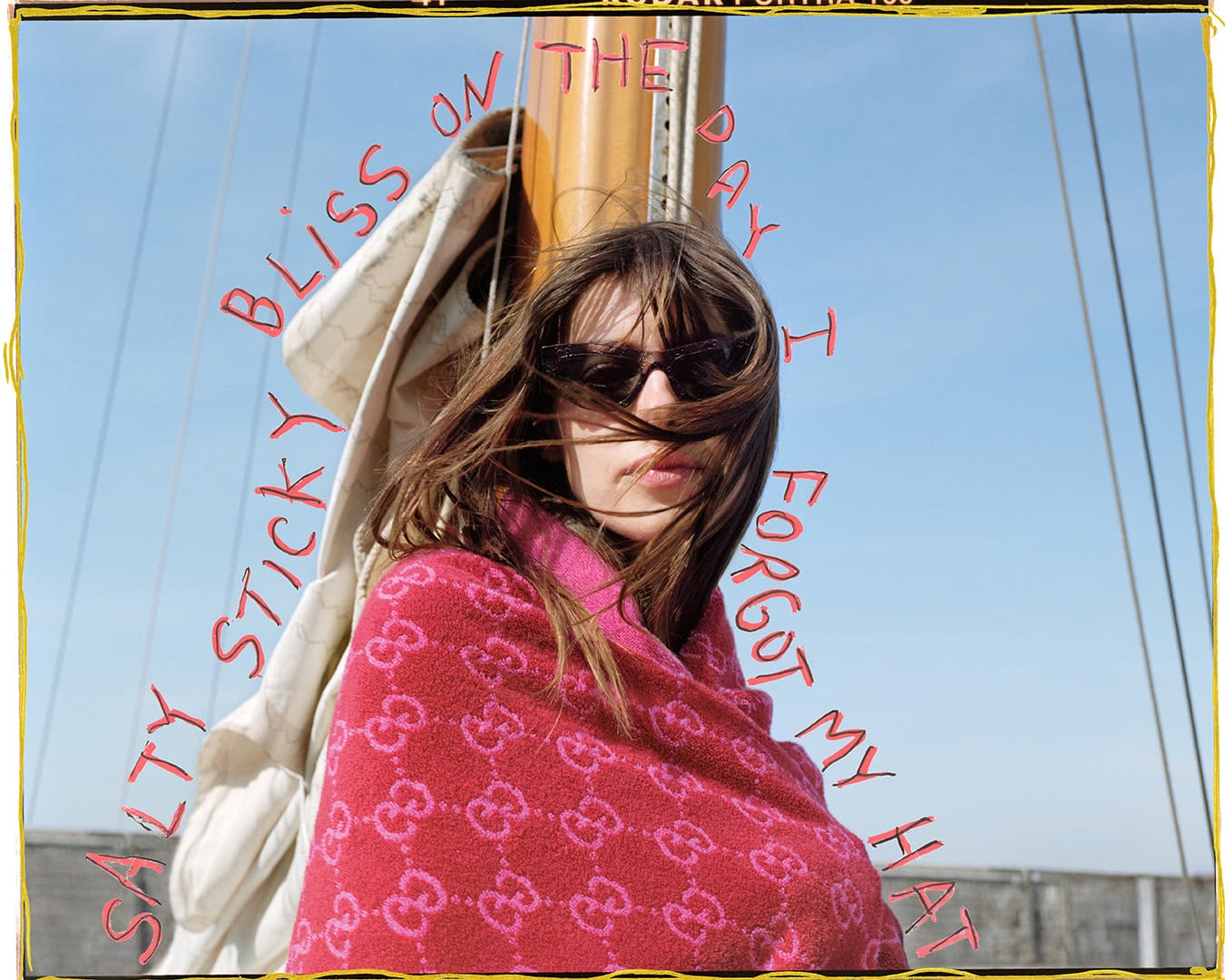 A woman wearing sunglasses wrapped in a pink patterned towel against a clear sky