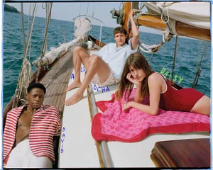 Three models lounging on the deck of a sailboat in the ocean for the Gucci Lido Spring 2025 campaign.