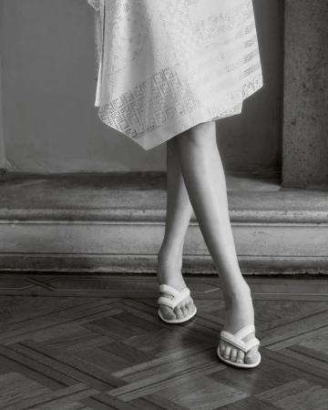 Close-up of model Achol Kuir wearing white sandals and a patterned skirt for Fendi Summer 2025 ad campaign.