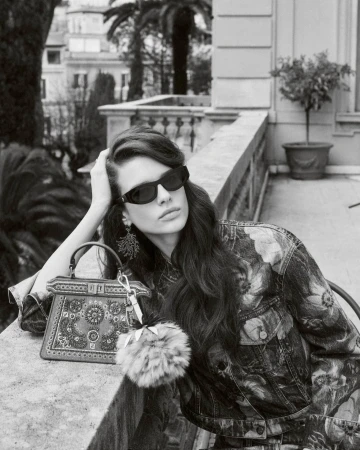 Monochrome fashion campaign image of model Achol Kuir leaning on a stone balcony with a Fendi handbag