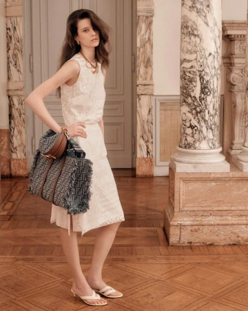 Model standing in an ornate interior holding a large patterned handbag for the Fendi summer 2025 ad campaign.