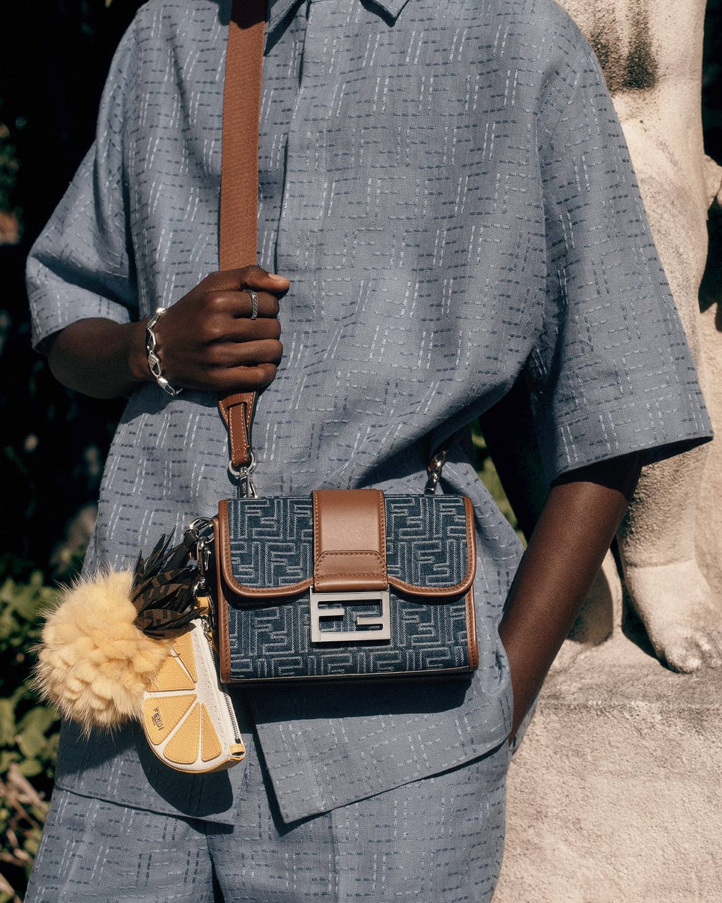 Model Achol Kuir wearing blue patterned shirt and shorts with a Fendi handbag for the Summer 2025 ad campaign.