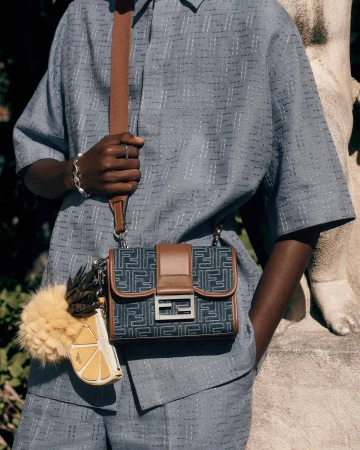 Model Achol Kuir wearing blue patterned shirt and shorts with a Fendi handbag for the Summer 2025 ad campaign.