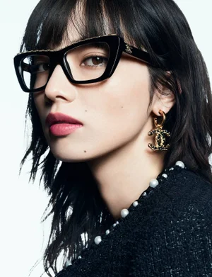 Nana Komatsu wearing black Chanel eyeglasses and pearl earrings against a white background