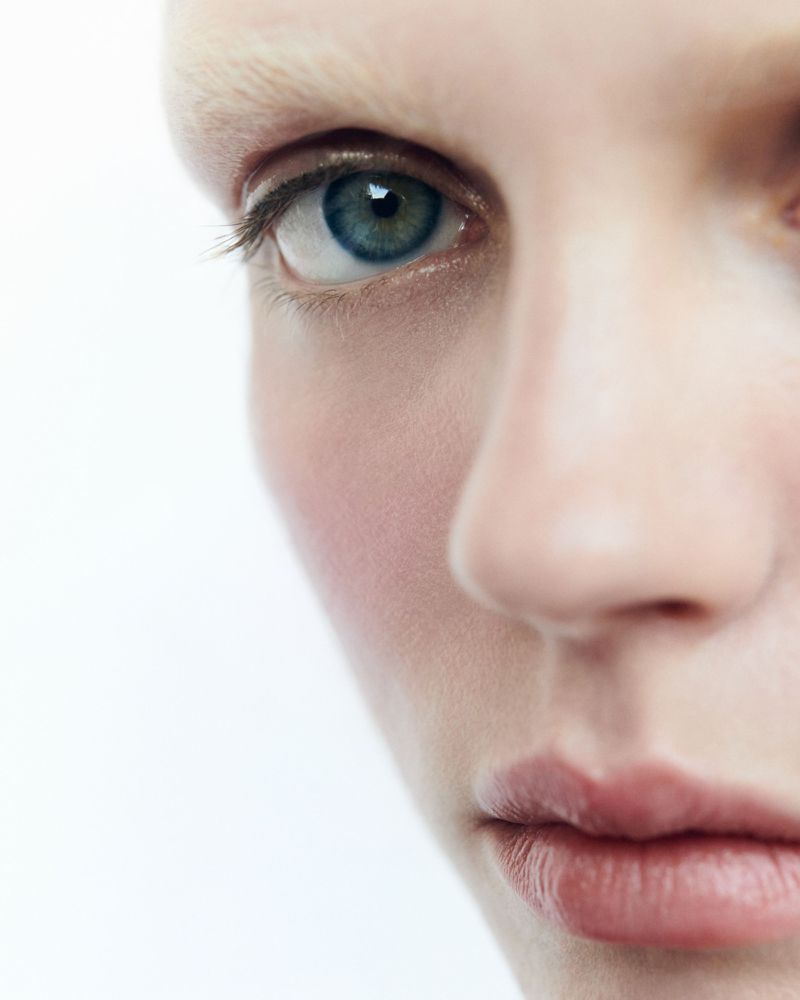 Close-up portrait of a person's face, showcasing detailed eye and skin texture against a bright white backdrop, highlighting beauty and skincare.