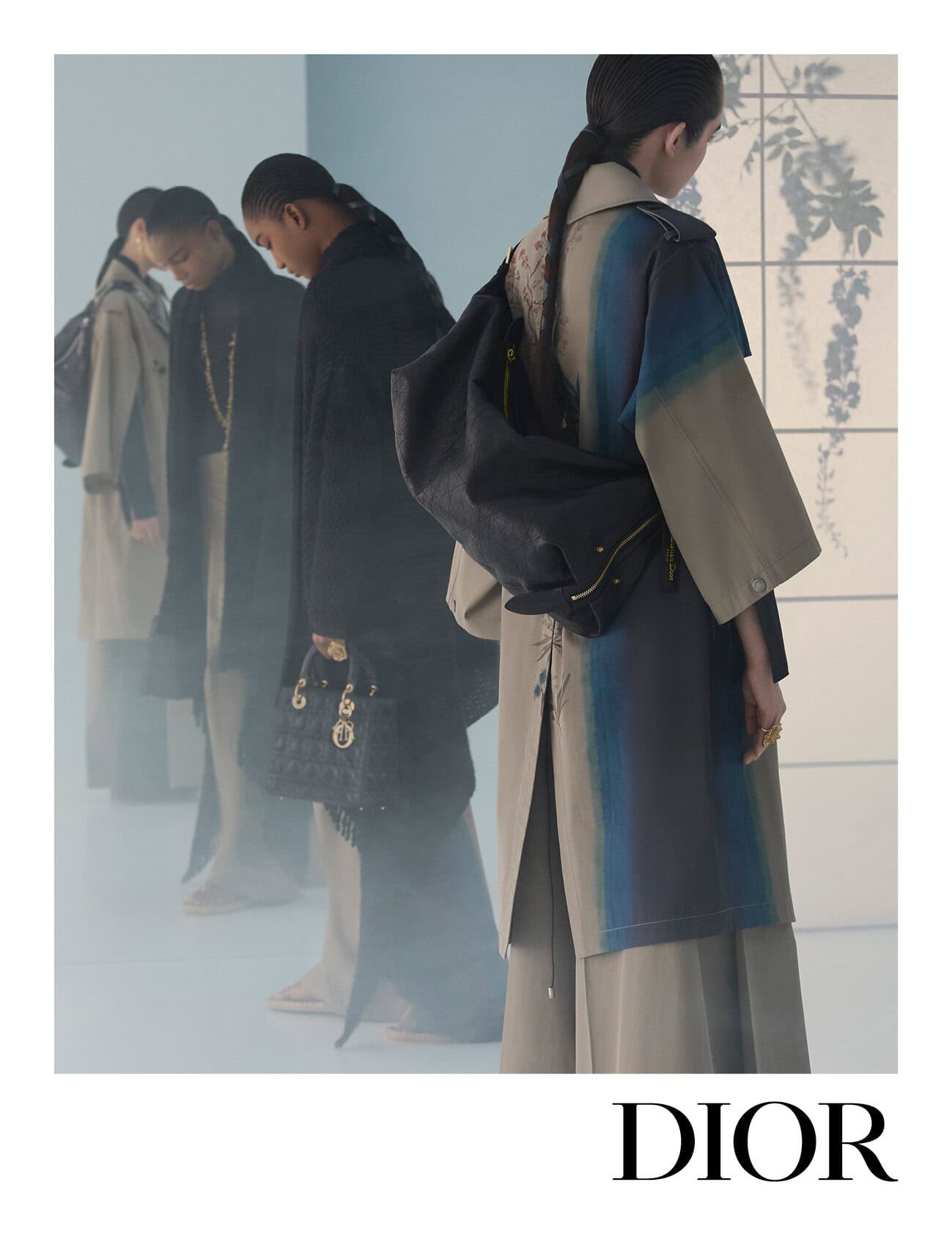 Four models in coats and carrying handbags stand in a row against a light background with floral shadows.