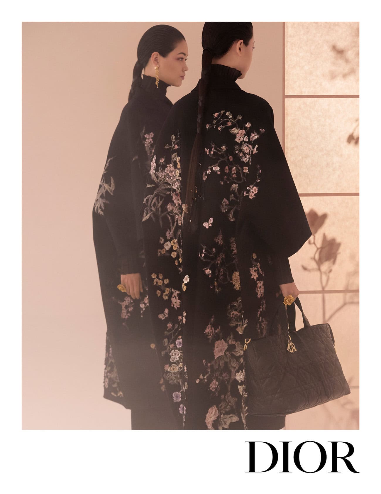 Two models in black embroidered coats posing for Dior Fall 2025 campaign, photographed by Yuriko Takagi.