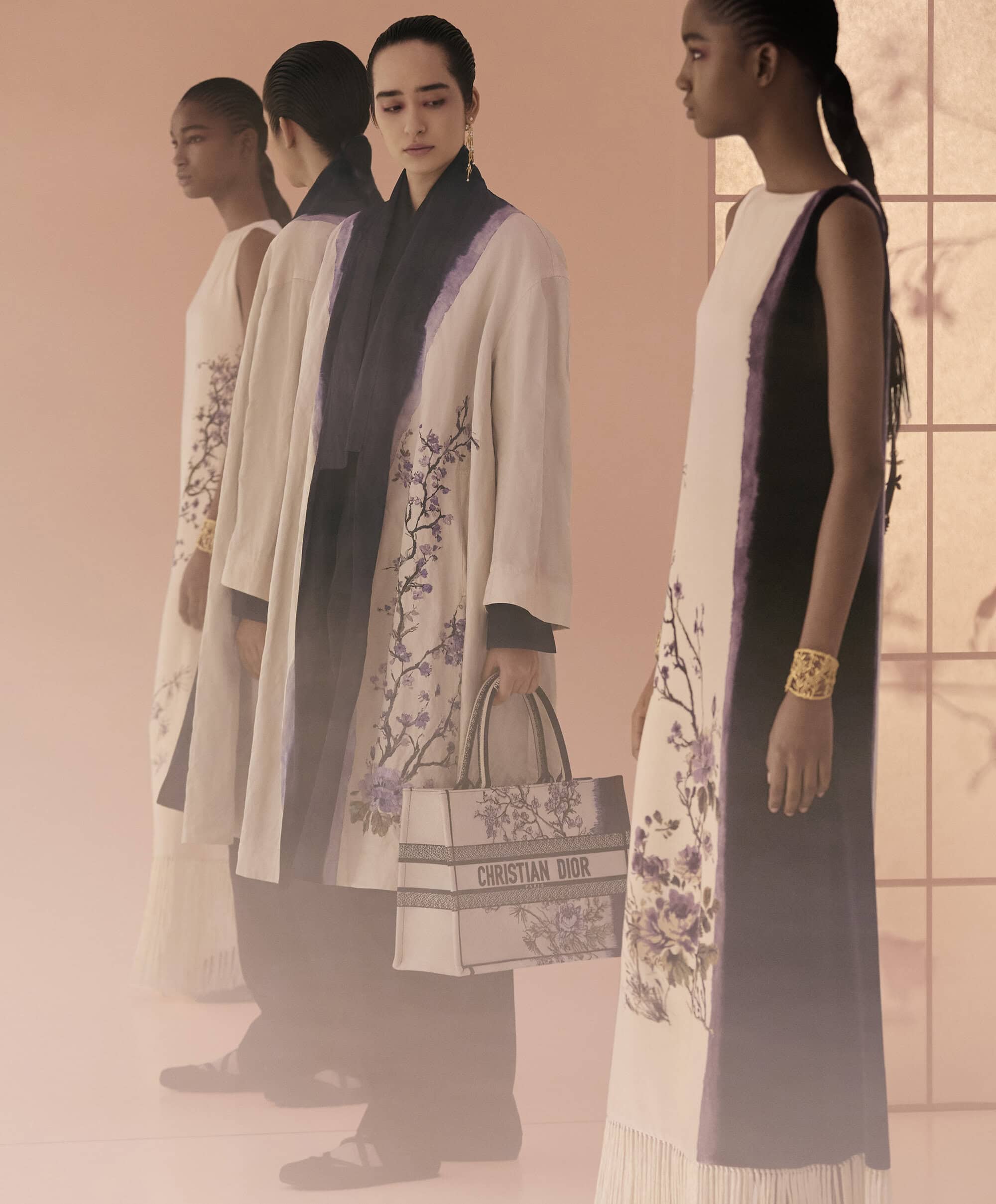 Four female models in patterned dresses and coats posing in a softly lit studio setting for Dior Fall 2025 campaign.