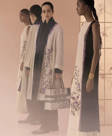 Four female models in patterned dresses and coats posing in a softly lit studio setting for Dior Fall 2025 campaign.
