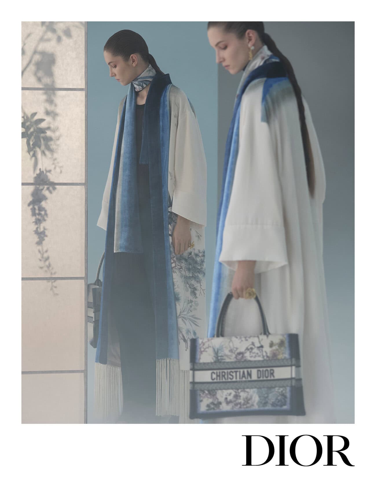 Models in white coats with blue scarves holding printed tote bags for Dior Fall 2025 campaign