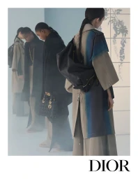 Four models in coats and carrying handbags stand in a row against a light background with floral shadows.