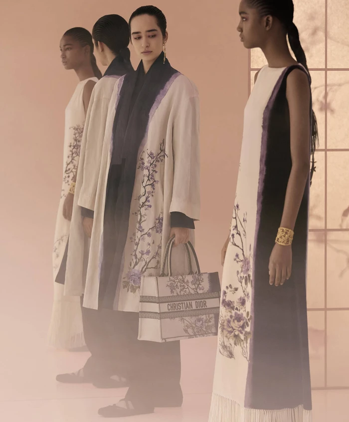 Four female models in patterned dresses and coats posing in a softly lit studio setting for Dior Fall 2025 campaign.