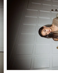 Model with long dark hair wearing a metallic top against a paneled wall in an interior setting