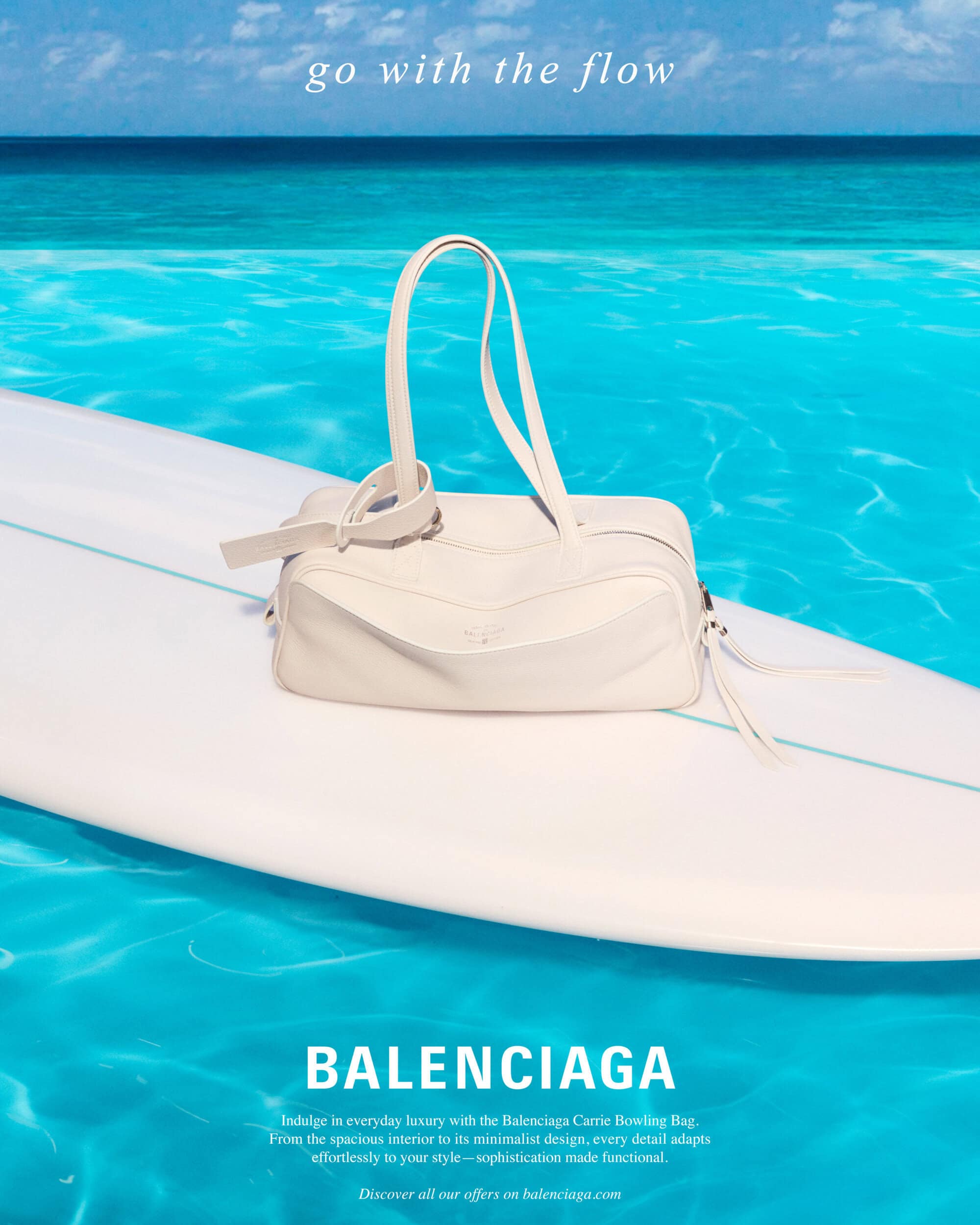 White handbag resting on a white surfboard floating over vibrant turquoise ocean water under a clear sky.