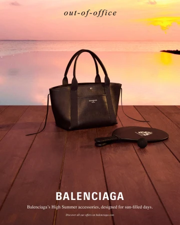 Black leather tote bag and paddle on a wooden deck overlooking a sunset ocean and horizon.