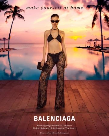 Model wearing a black bikini top and sheer lace pants holding a black clutch by an infinity pool at sunset.