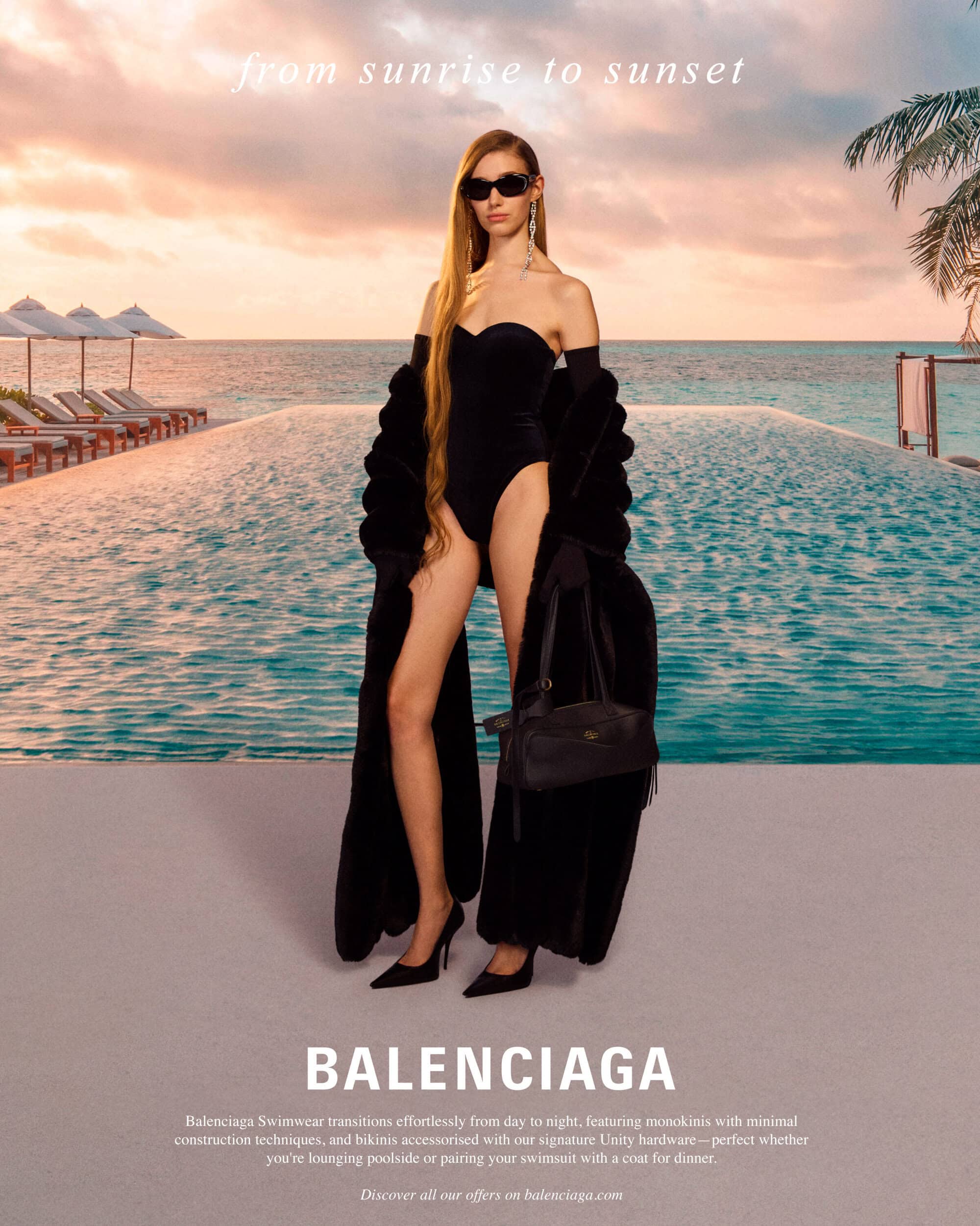 Model in black swimsuit and sunglasses wearing a long dark coat by a resort pool at sunset for Balenciaga High Summer 2025 Ad Campaign
