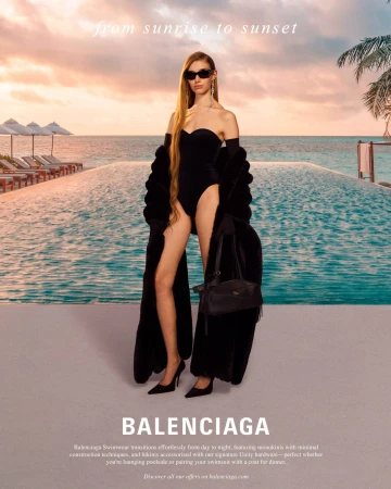 Model in black swimsuit and sunglasses wearing a long dark coat by a resort pool at sunset for Balenciaga High Summer 2025 Ad Campaign