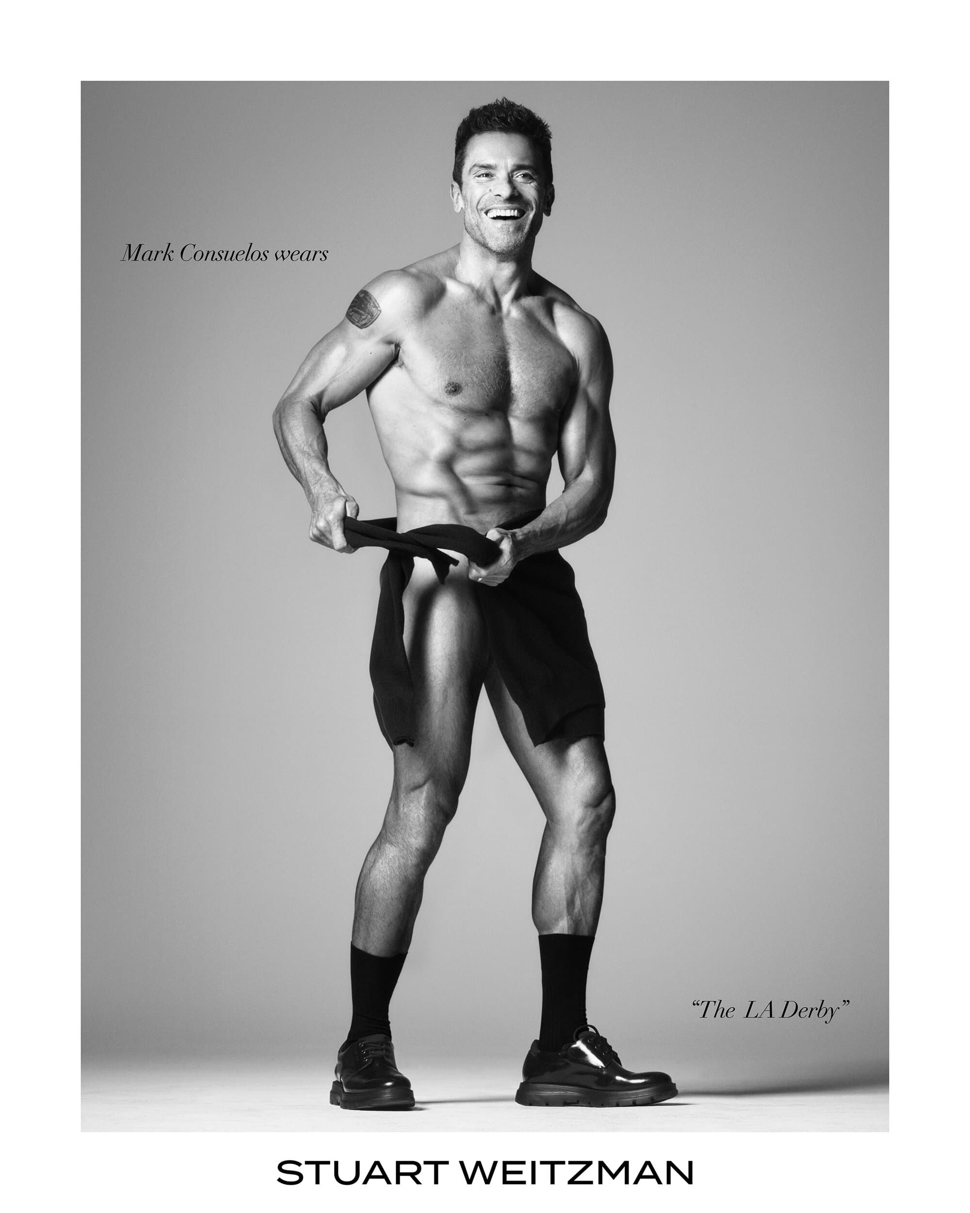 Mark Consuelos wearing black socks and shoes against a grey seamless studio background for Stuart Weitzman