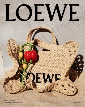 Loewe woven straw handbag with red tomato charm on sand background
