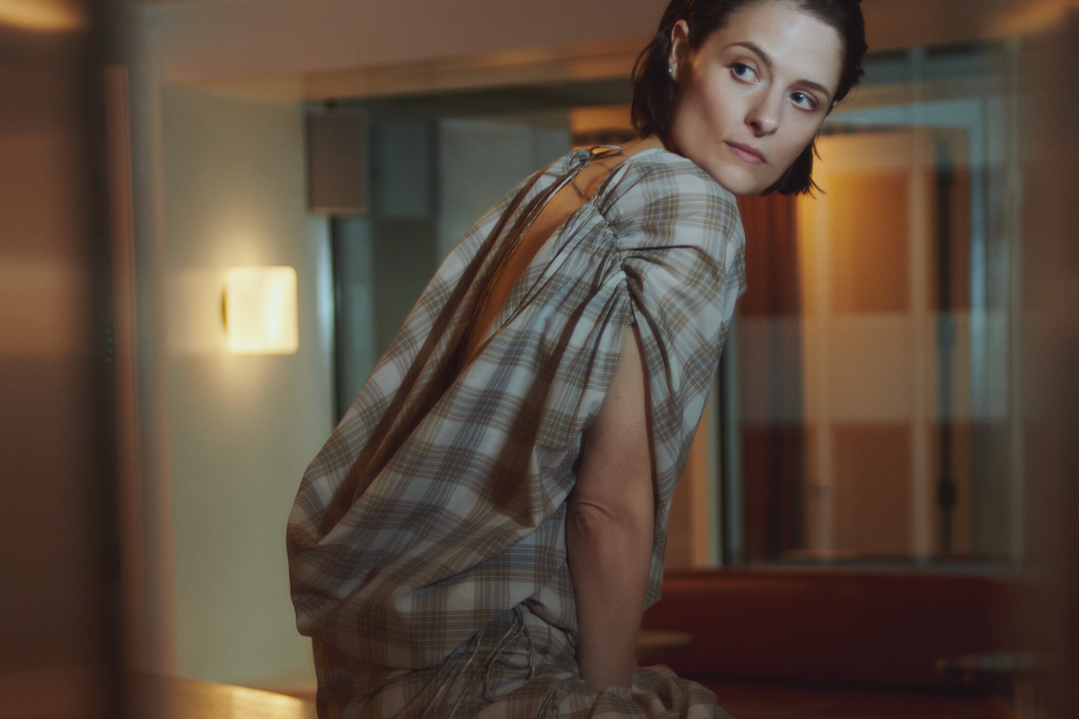 Model Louisa Jacobson in a plaid top posing indoors for Kallmeyer Spring 2025 campaign