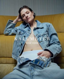 Model wearing a denim jacket and white underwear seated against a yellow sofa for Kallmeyer