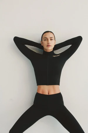 Model Irina Shayk wearing a black long sleeve athletic top against a plain white background