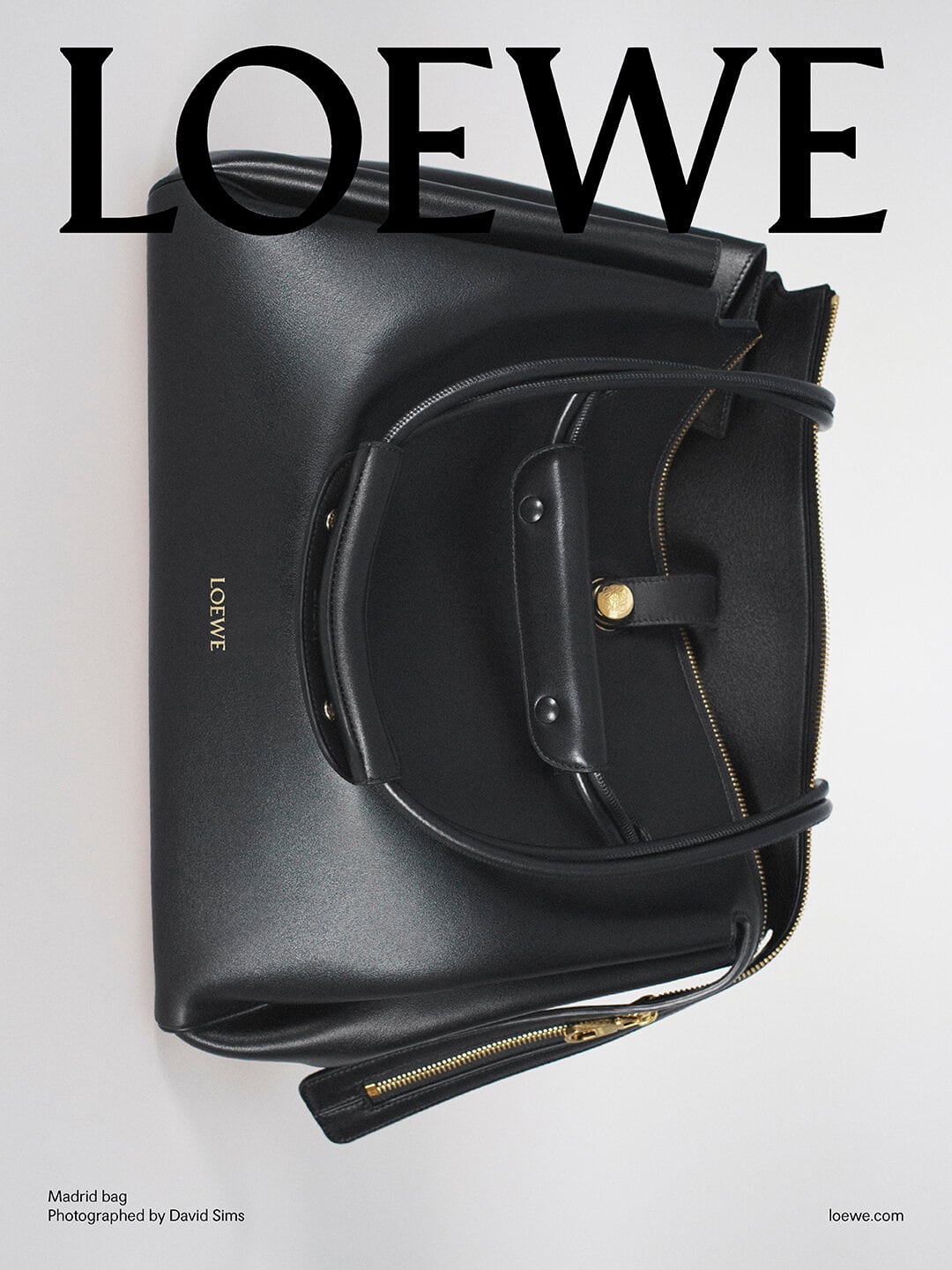 Black leather handbag with twin top handles against a clean white seamless backdrop under soft lighting.