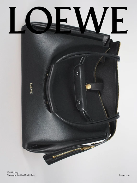 Black leather handbag with twin top handles against a clean white seamless backdrop under soft lighting.
