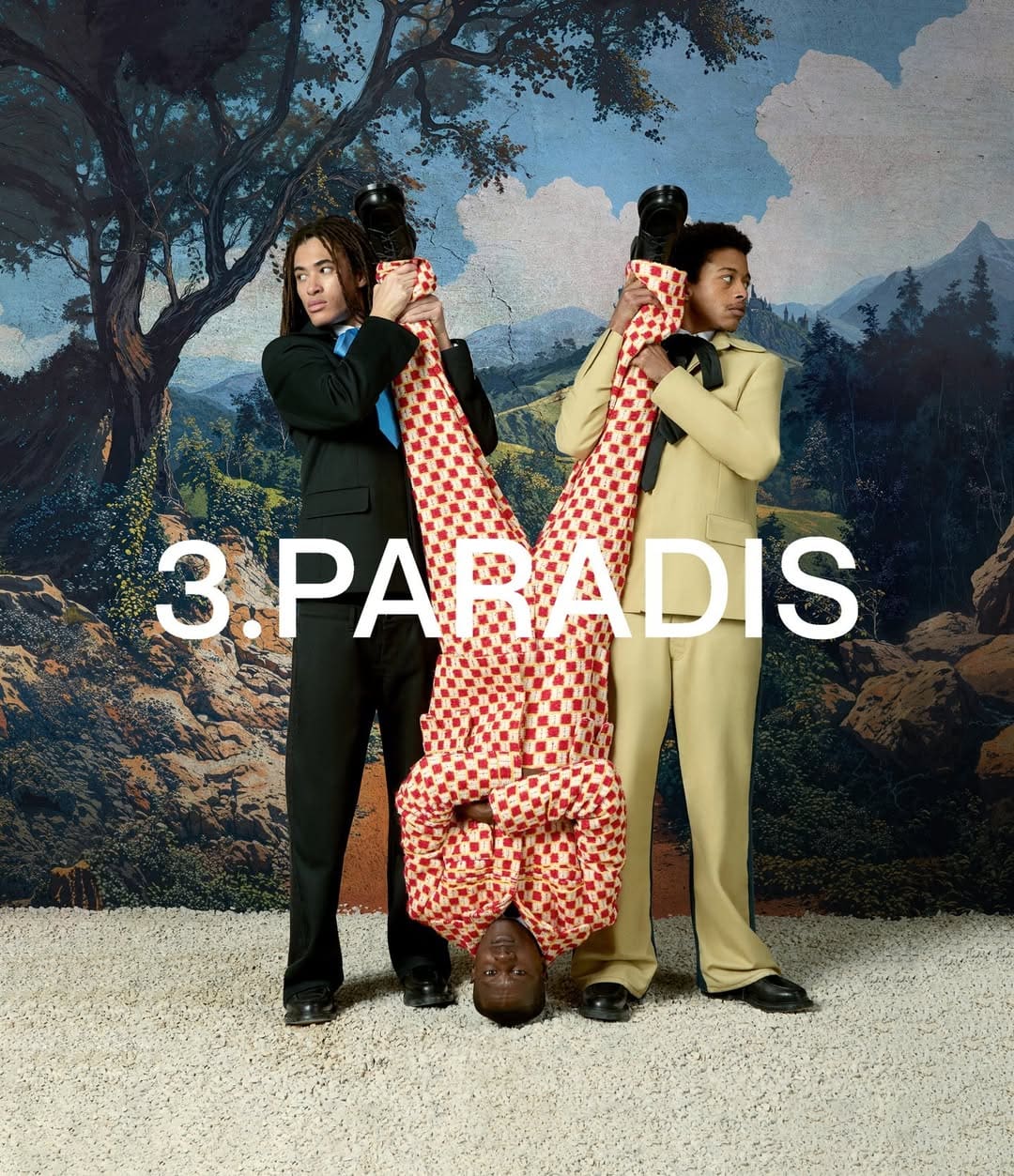 Three male models in suits posing against a painted landscape backdrop, with one model upside down holding his legs.