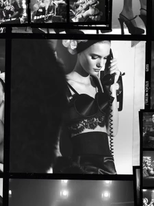 Model in dark lingerie holding a rotary telephone handset against a light background with contact sheet borders