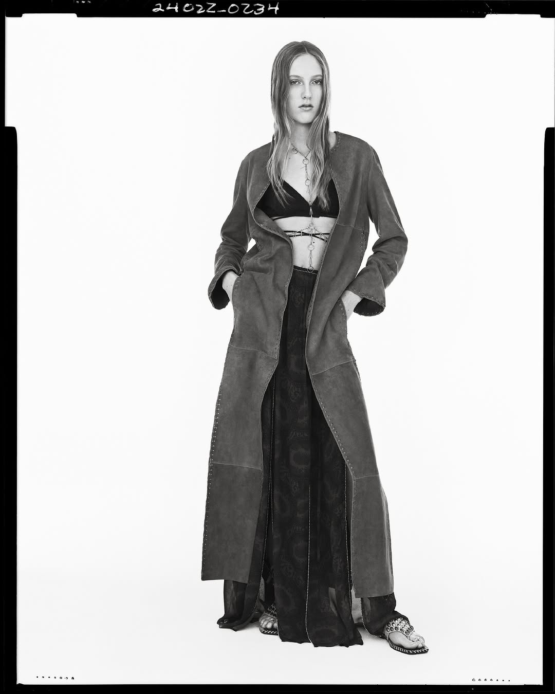 Model in long coat and patterned skirt against a white seamless background for Zara spring campaign