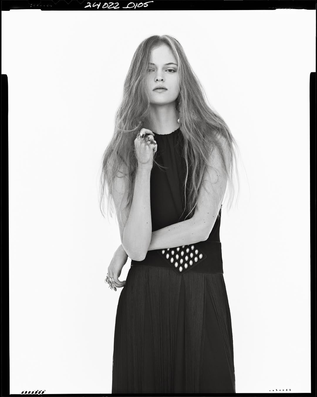 Model with long hair wearing a black sleeveless dress against a white studio background for Zara Spring 2025 campaign.