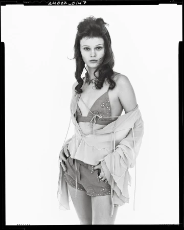 Model in layered summer outfit wearing decorated shorts against a white backdrop