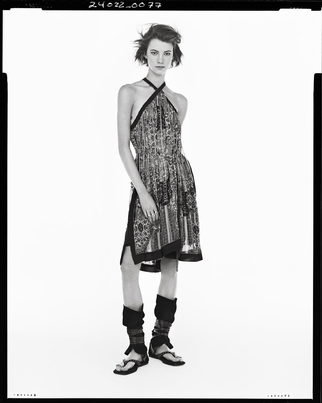 Model in printed halter dress and dark sandals against a white backdrop for the Zara Studio Spring 2025 ad campaign.