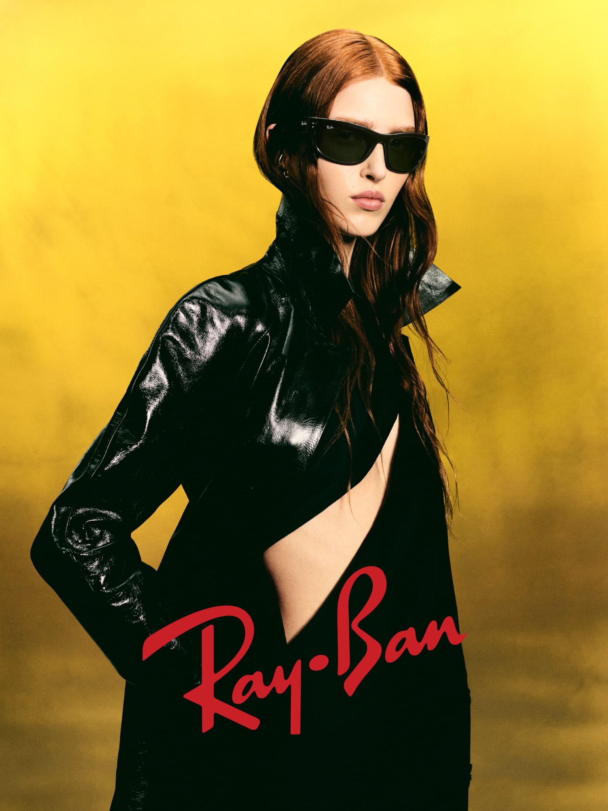 Model wearing black sunglasses and a dark glossy coat against a vibrant yellow gradient background for Ray-Ban