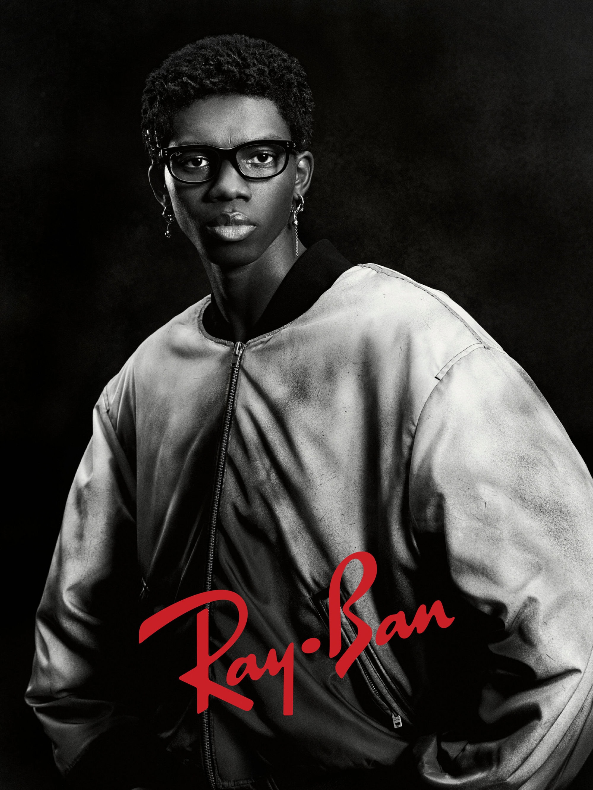 Black and white portrait of a young Black man wearing dark glasses and a bomber jacket for Ray-Ban