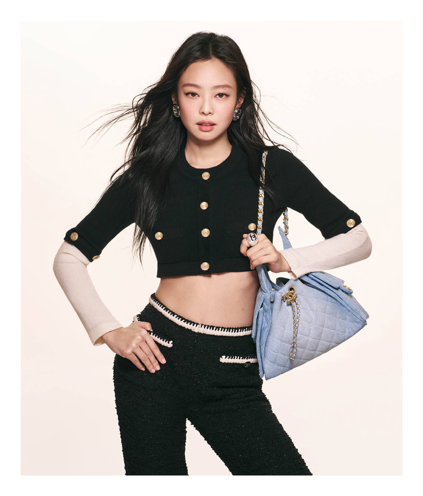 Jennie wearing a black cropped cardigan and holding a light blue Chanel quilted handbag against a seamless white background