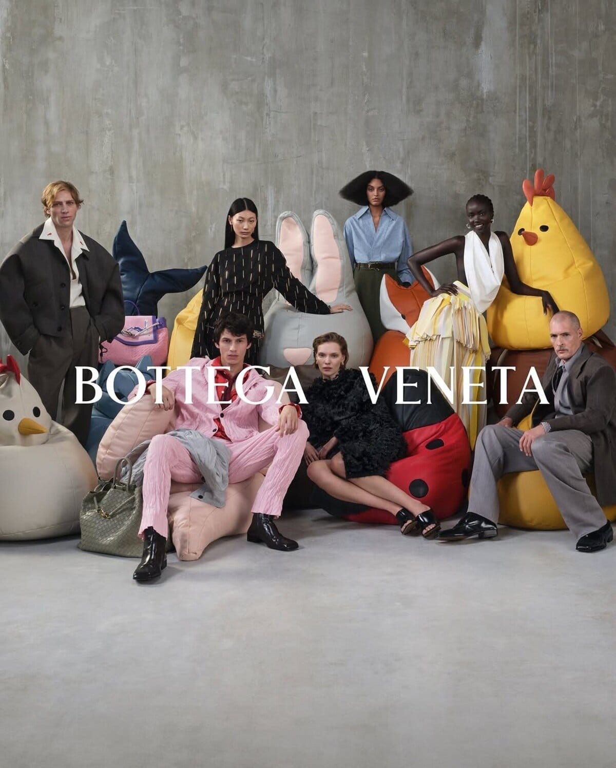 Group of models posing among oversized animal beanbag chairs against a concrete wall for Bottega Veneta campaign