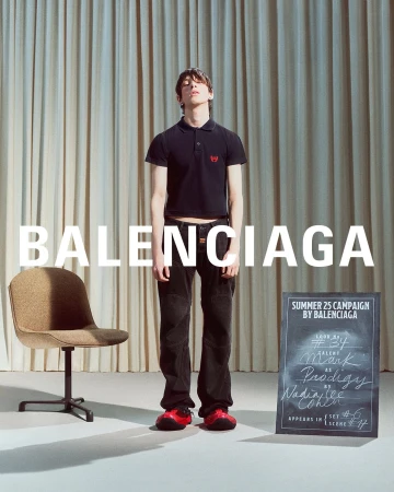 Model wearing black polo shirt and dark trousers standing against pleated curtains with Balenciaga typography overlay