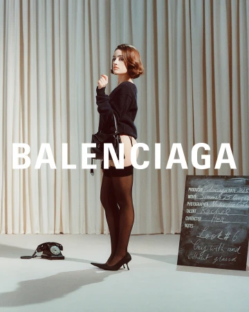 Model Rachel Sennott wearing a black sweater and stockings holding a handbag against a pleated curtain backdrop with text.